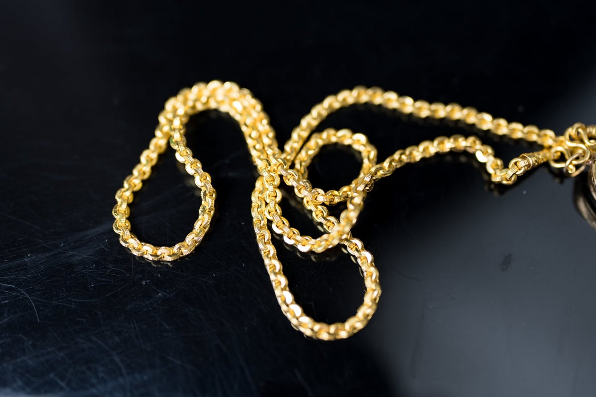 Gold chain necklace on a black background. Top view