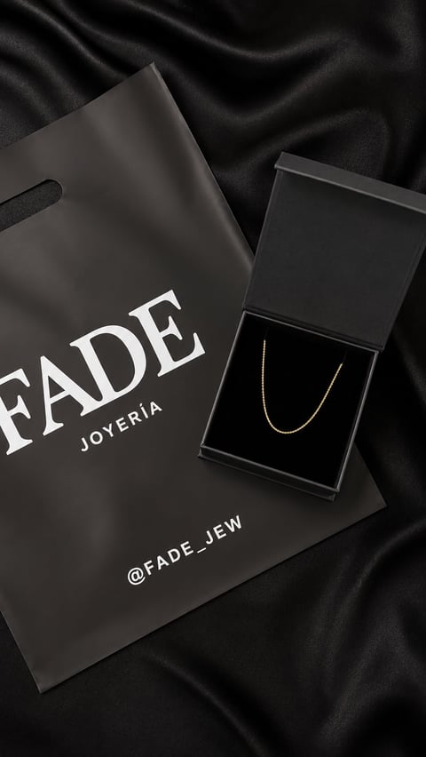 Fade Joyeria luxury jewelry packaging with a delicate gold chain necklace in an open black box on black fabric background