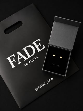 Fade Joyeria luxury jewelry brand black shopping bag with gold stud earrings displayed in open black box packaging