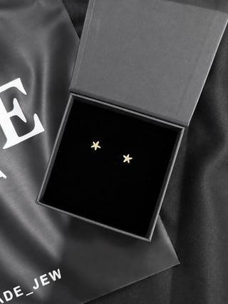 Gold star stud earrings in an open gray gift box