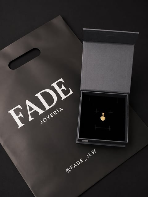 Fade Joyeria luxury jewelry brand packaging with gold heart pendant in gray box on black shopping bag